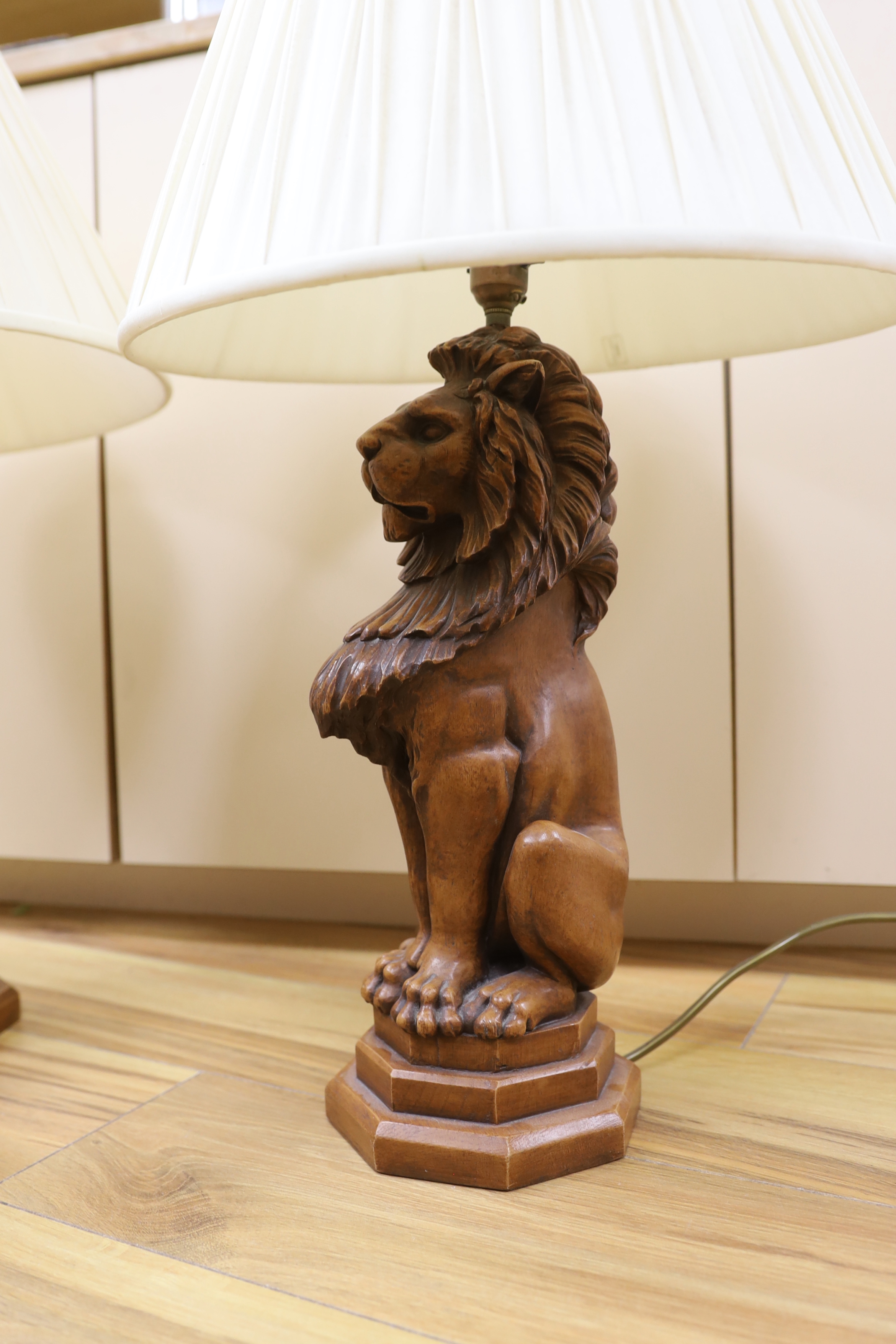 A pair of faux carved lion table lamps, 65cm high including shades